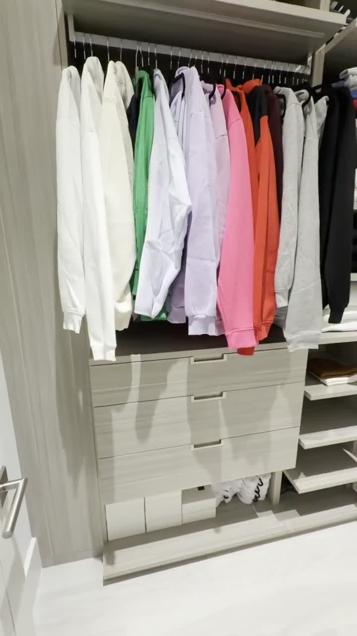 The finished closet: hoodies and sweatshirts hanging in a color gradient, folded stacks on shelves, the floor completely clear.