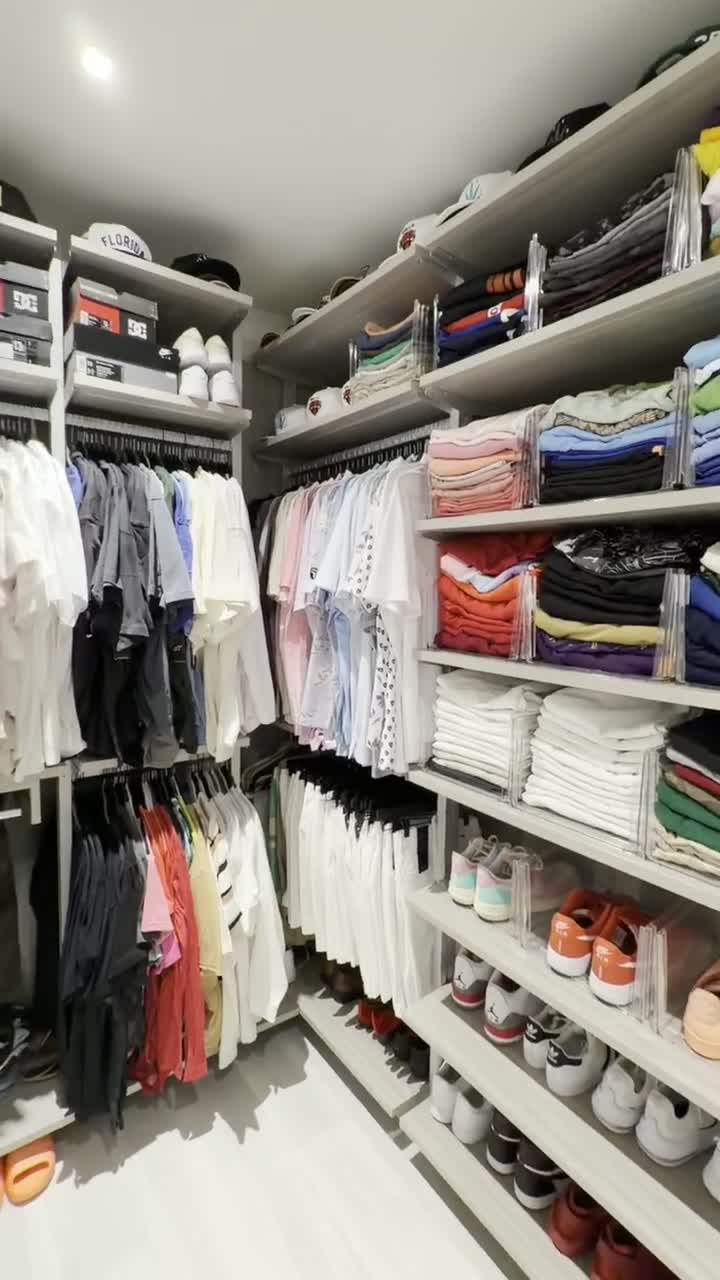 The finished closet in full: folded stacks with clear dividers, shirts sorted by color, sneakers lined up on open shelves.